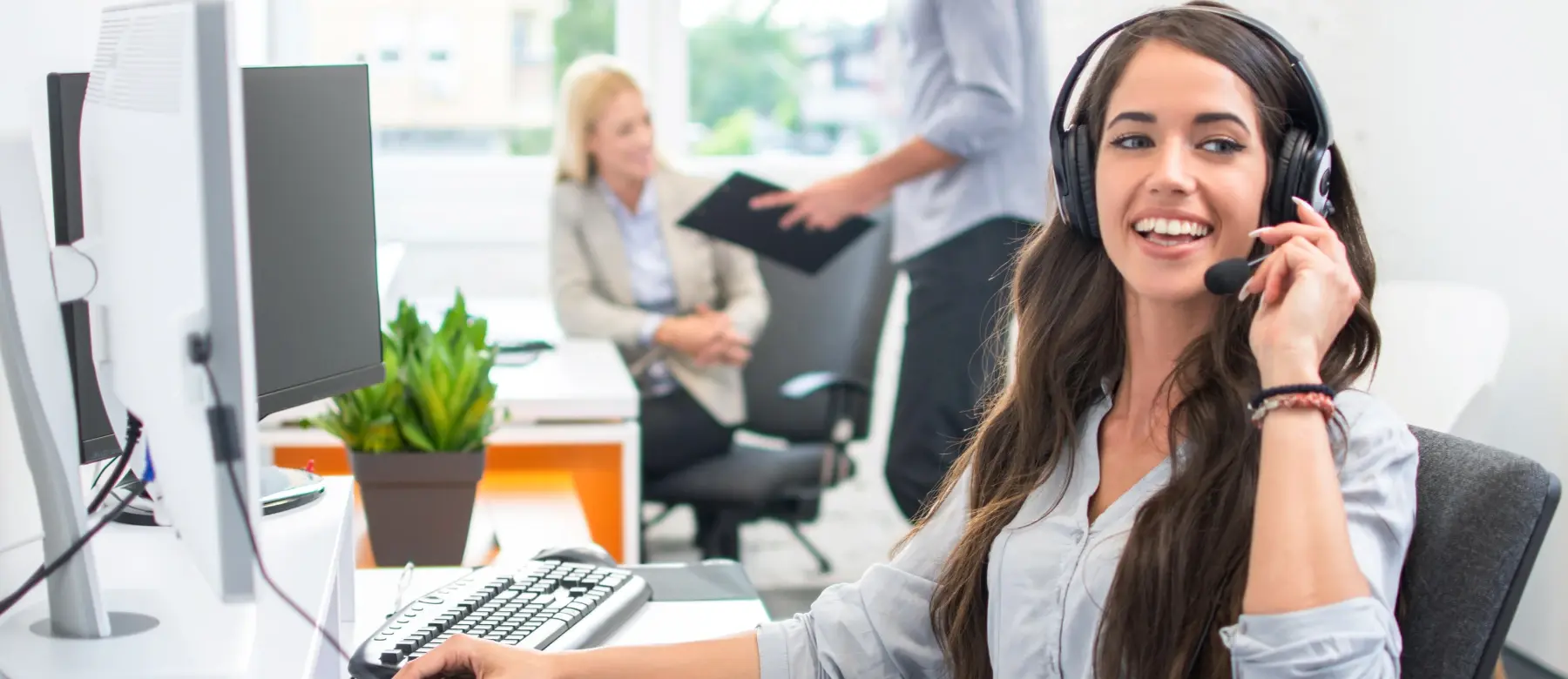 A ChamberMate support specialist wearing a headset, smiling at her desk